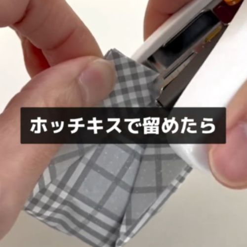 上部を折りたたんで書類とじ器で留める様子