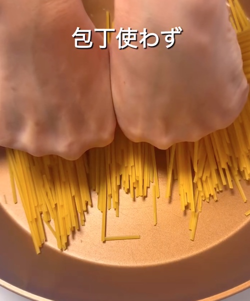 半分に割ったパスタをフライパンに入れている様子