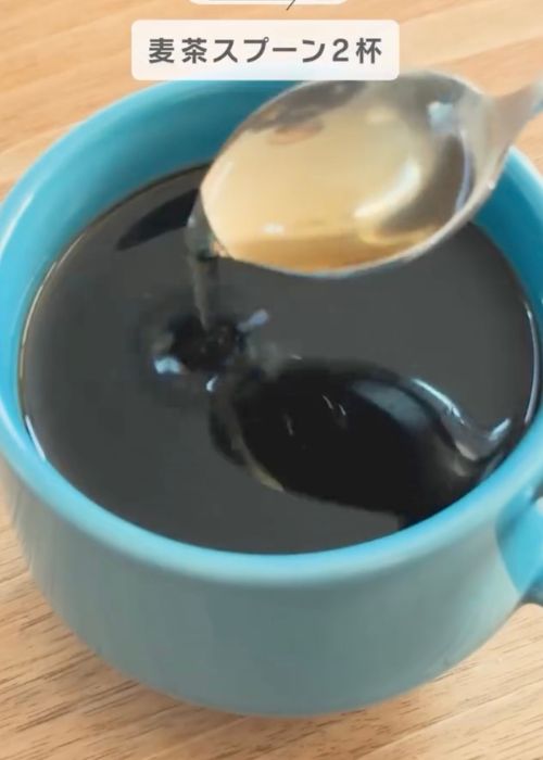 コーヒーの入ったカップにスプーンで麦茶を入れる様子