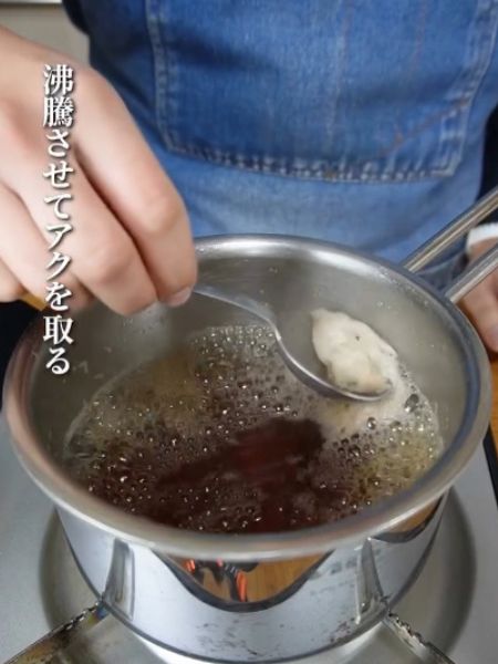 シイタケだしと調味料を沸騰させてアクを取る様子