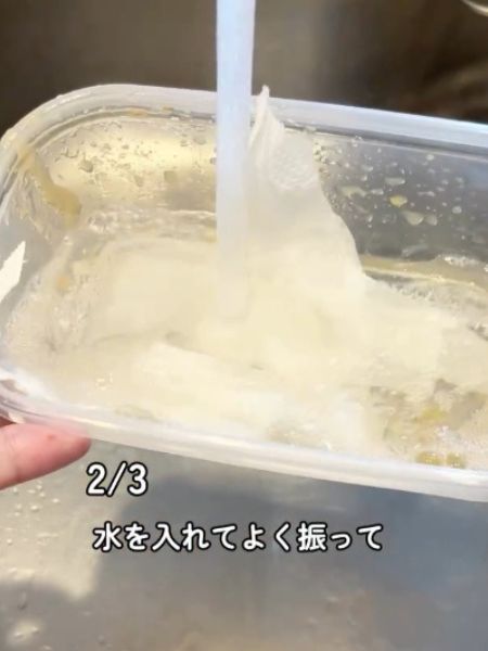 小さく切ったキッチンペーパーと食器用洗剤を入れた保存容器に水を入れる様子