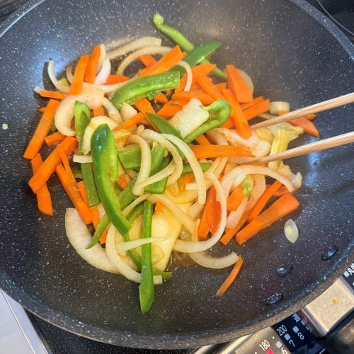 フライパンで野菜とたれを炒め合わせる様子