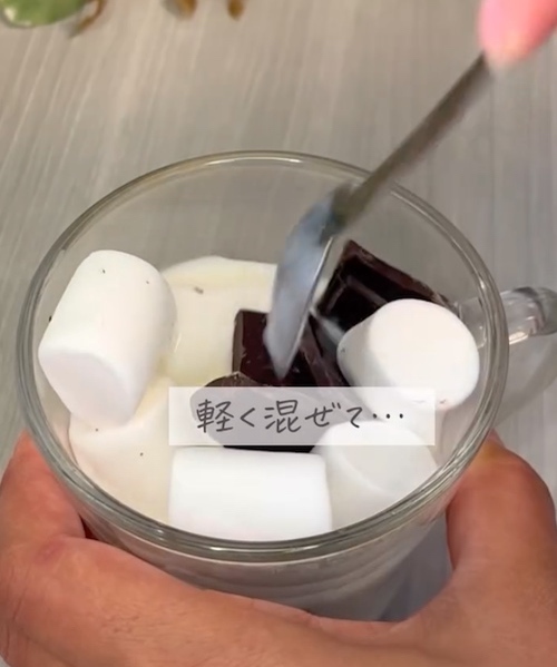 カップの中の牛乳とマシュマロとチョコレートを混ぜる様子