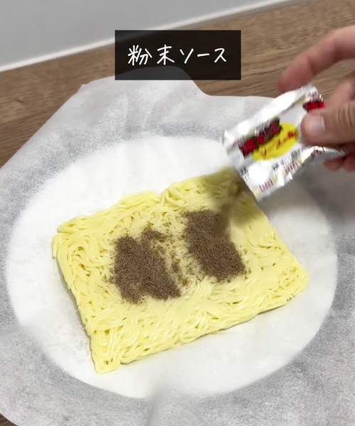 焼きそばの麺に粉末ソースをかける様子