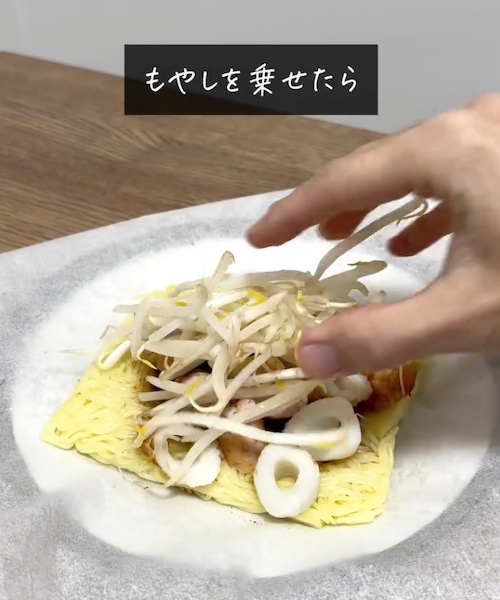 焼きそばの麺の上に具材をのせる様子