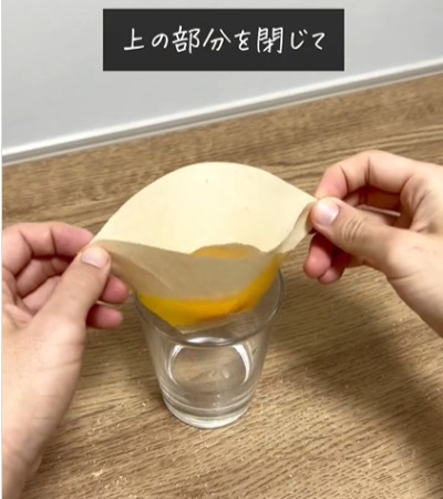 卵の入ったコーヒーフィルターの上部を折る様子