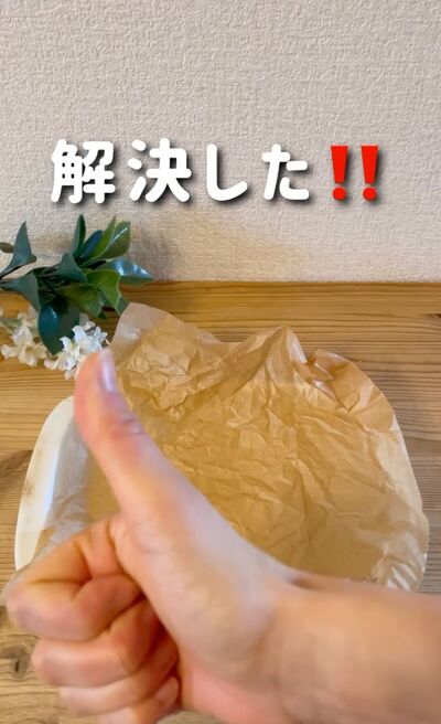 くしゃくしゃの状態のクッキングシートと親指を立てた手元