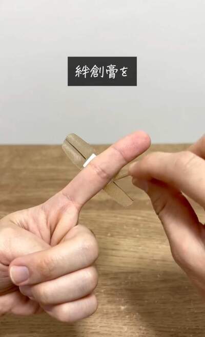 切り込みを入れた絆創膏を指に巻く様子