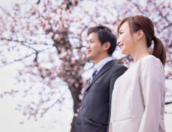 桜の木の下に立っているスーツ姿の男性と女性の写真