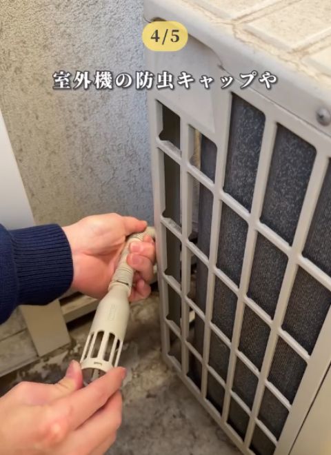 室外機に付いているドレンホースに防虫キャップを取り付ける様子