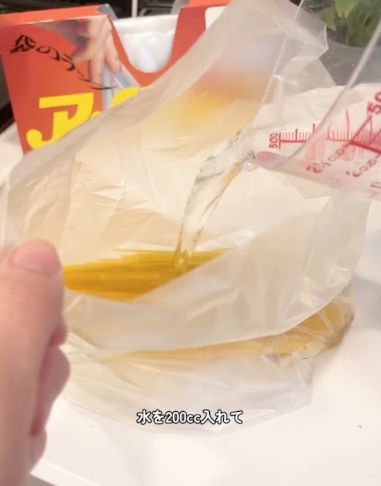 パスタが入った耐熱性ポリ袋に水を入れている様子