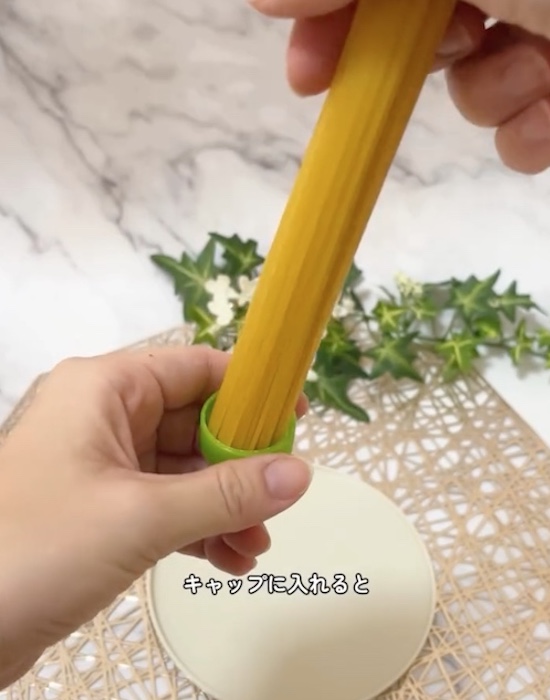 ペットボトルのキャップでパスタの量を量る様子