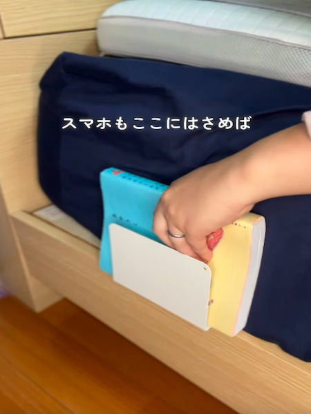 ベッドとマットレスの間に挟んだブックエンドに本を入れる様子
