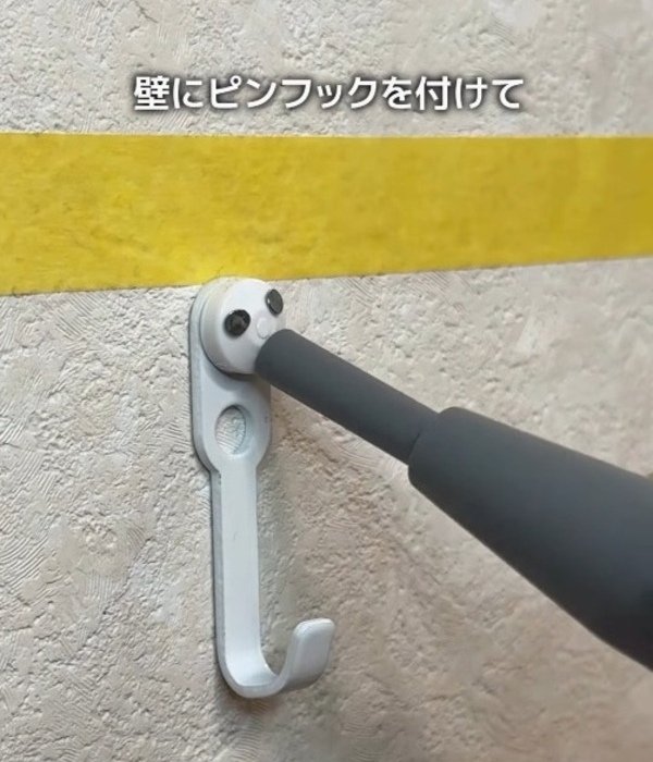 壁にピンフックを取り付けている様子