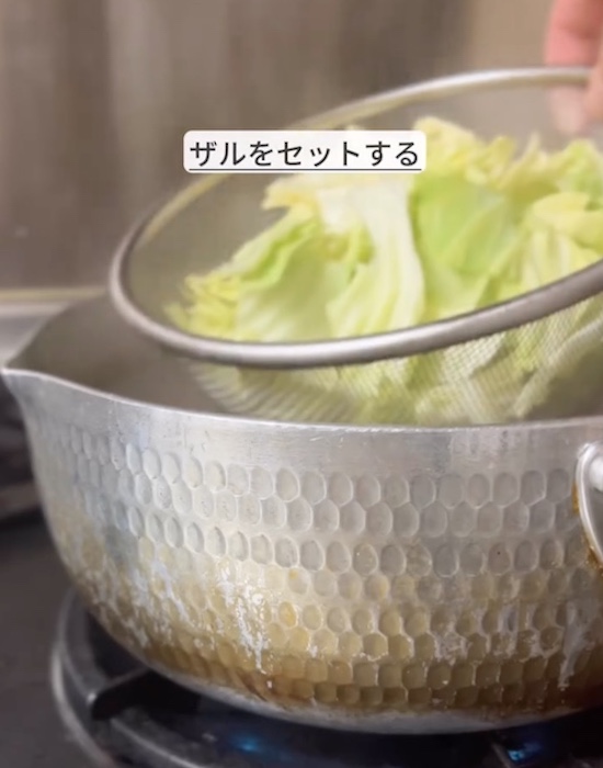 鍋の中に野菜を入れたザルを入れる様子