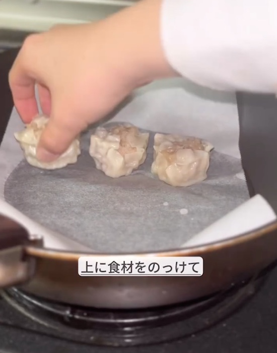水の浸ったクッキングシートにシュウマイを置く様子