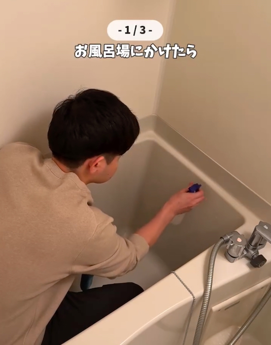 お米の研ぎ汁が入ったスプレーを浴槽に吹き付けている男性