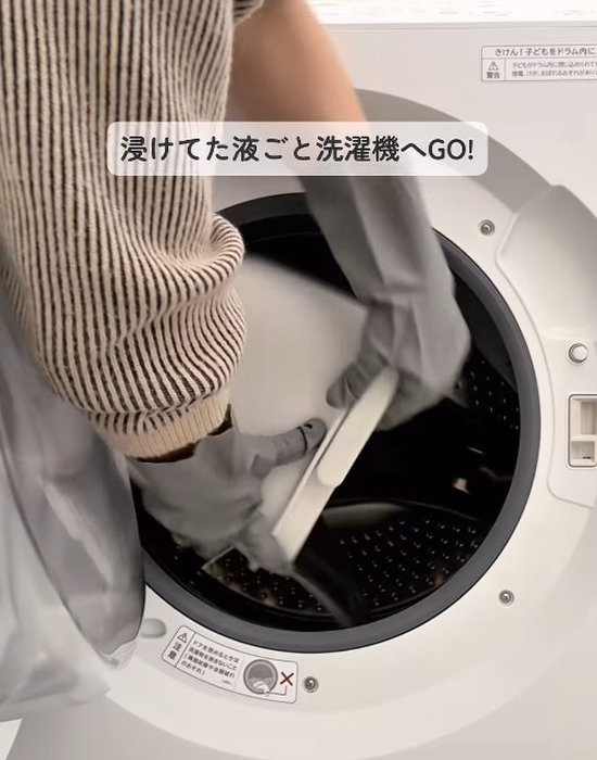 バケツに入った枕カバーを洗濯機に入れている様子