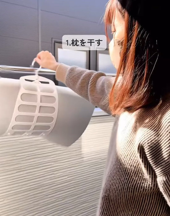 ベランダに枕を干す女性