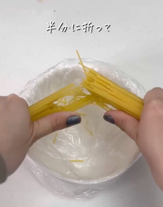 パスタを手で半分に折る様子