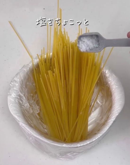 半分に折ったパスタと水を入れた『アイラップ』に塩を入れる様子