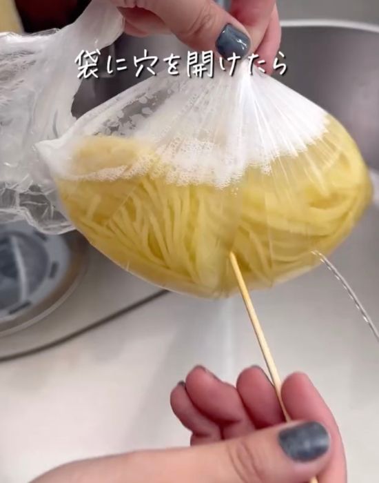 電子レンジで加熱したパスタと水が入った『アイラップ』の袋につまようじで穴を開けて水を出す様子