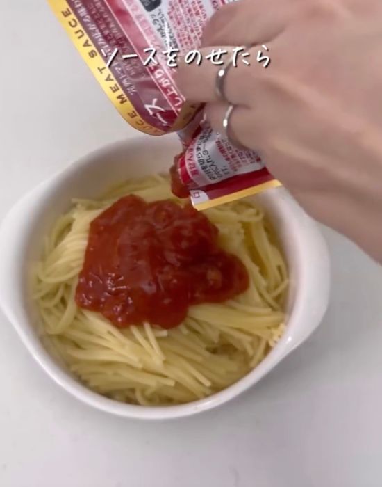 お皿に入れたパスタに温めたパスタソースをかける様子