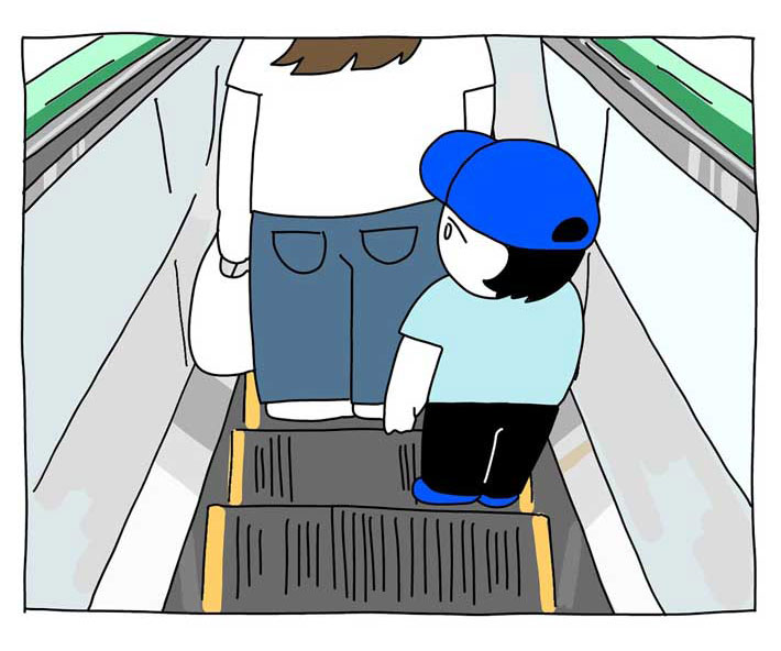エスカレーターの端に立つ子供