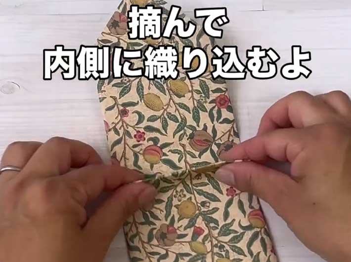 デザインペーパーを裏返し、折り目を付けた部分をつまんで、内側に折り込む