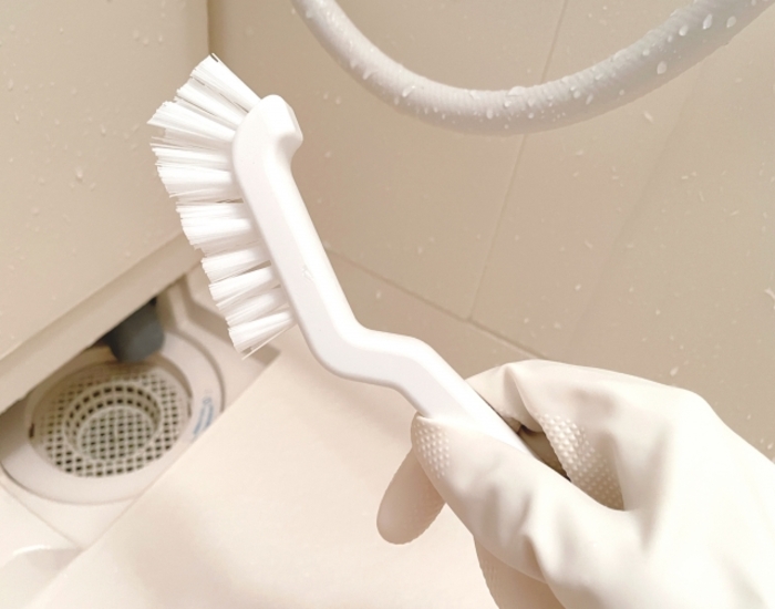 排水口の前でブラシを手にしている様子
