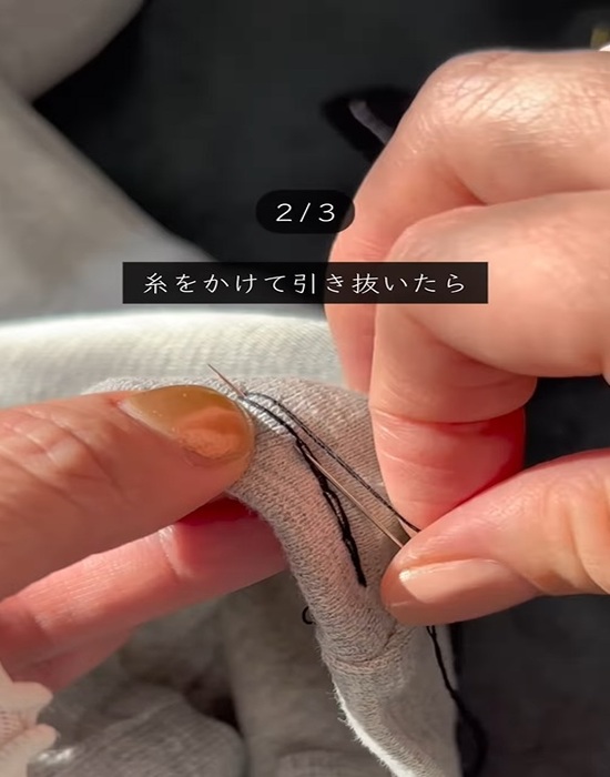 ズボンに通した針から糸を抜く様子