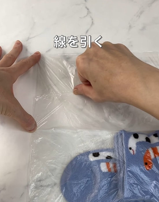 ビニール袋に爪で線を引いている様子