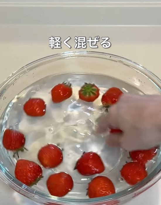 ボウルの中の水とイチゴを混ぜる様子