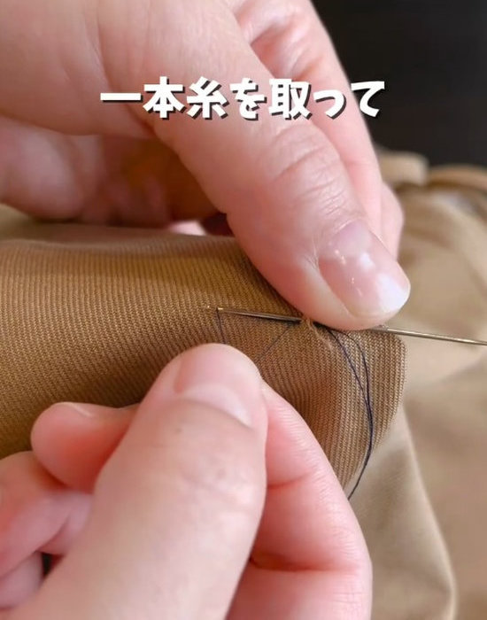 服に通した糸を持つ人の手