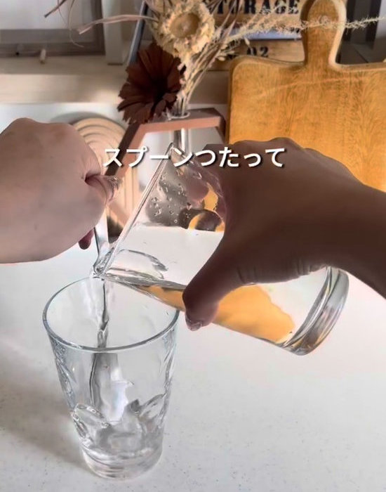 スプーンを使ってコップからコップに水を注いでいる様子