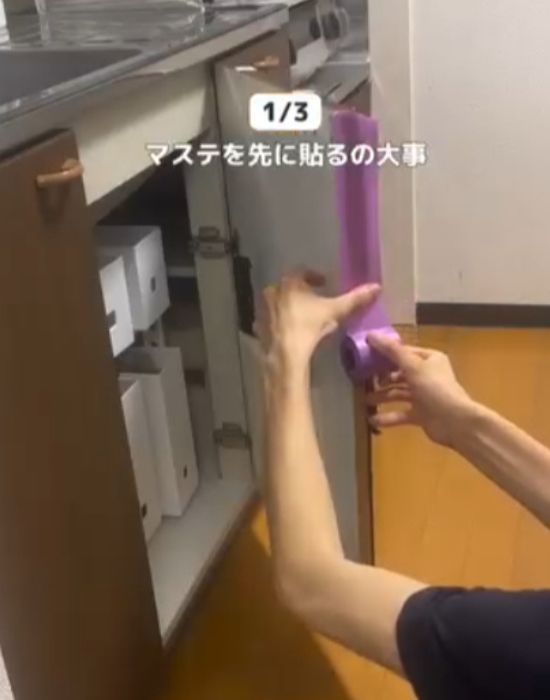 シンク下の扉にマスキングテープを貼る様子