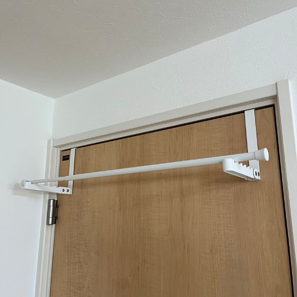 ドアの上部にかけたフックにつっぱり棒をのせた様子