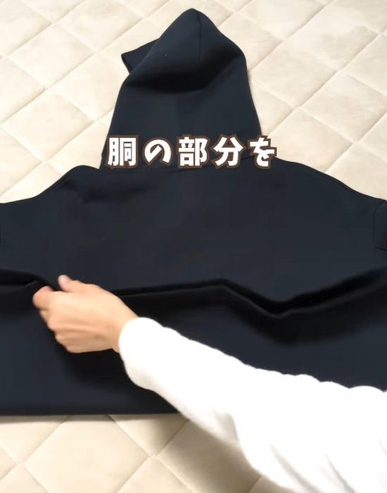 パーカーの背中側を上にして広げて置く様子