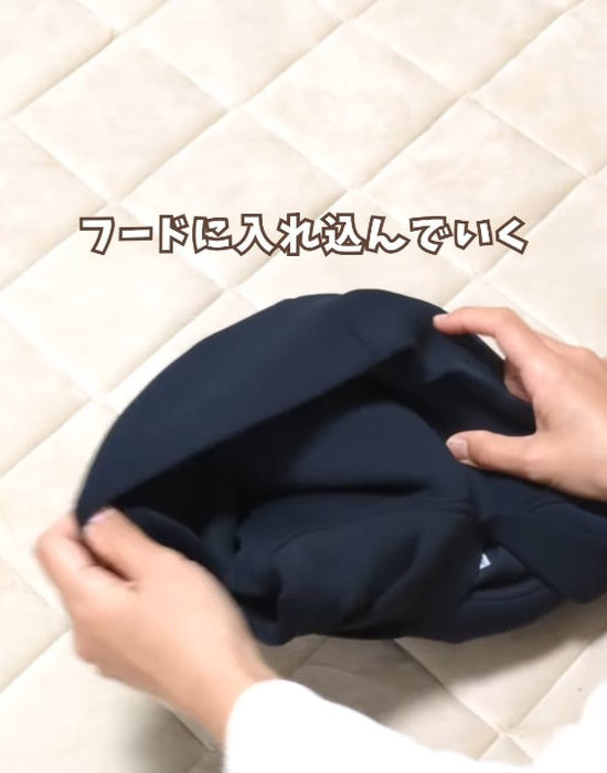 畳んだパーカーの胴の部分をフードの中に入れ込む様子
