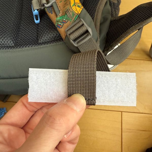 適当な長さに切った面ファスナーをリュックのひもの端に合わせる様子