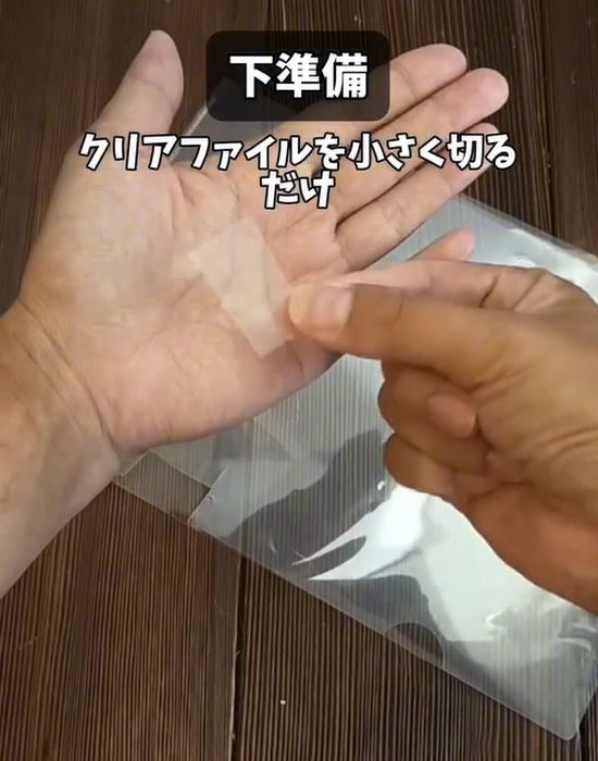小さくカットしたクリアファイルを持つ人