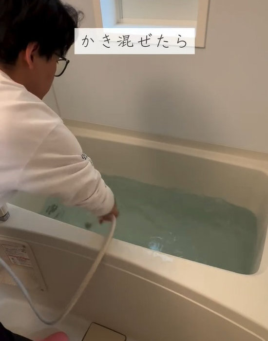 シャワーヘッドで浴槽の水を混ぜている様子
