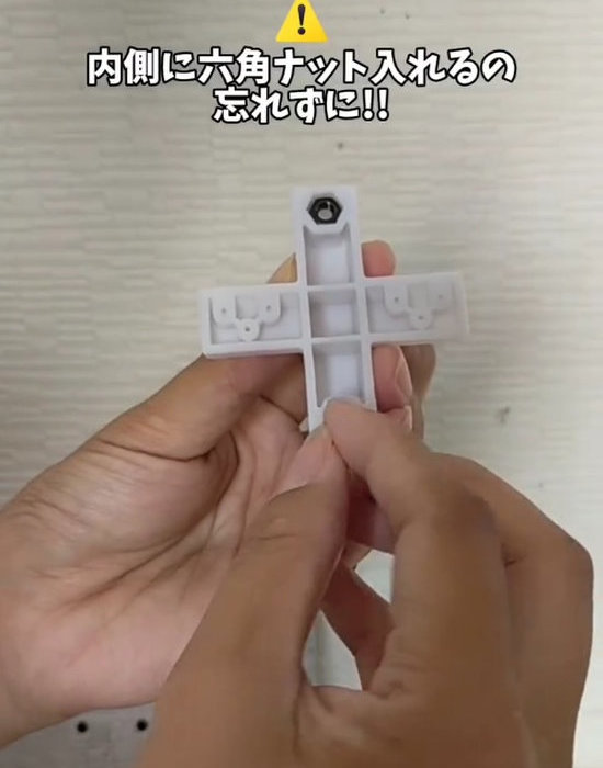 壁面取付けパーツの内側に六角ナットを入れる様子