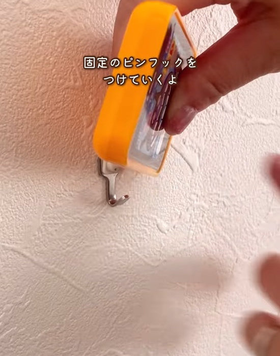 壁にピンフックを設置する様子