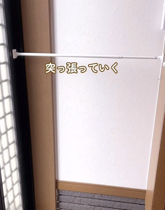 つっぱり棒を壁面ガードに引っかける様子