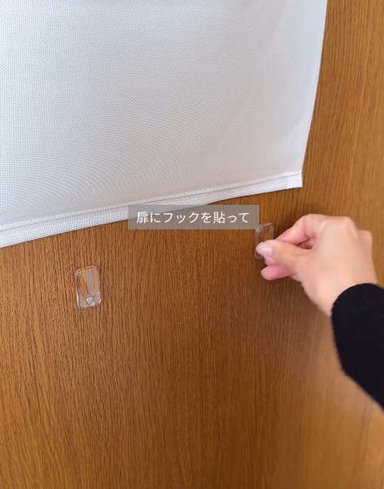 扉の裏側にフックを貼り付ける様子