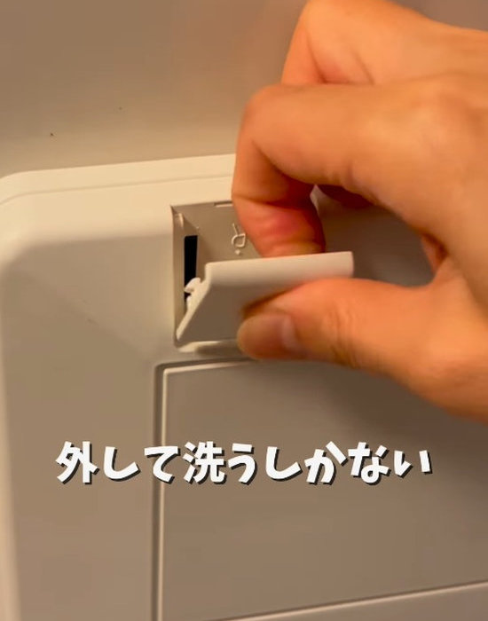 換気扇カバーのネジに付いたカバーを外す様子
