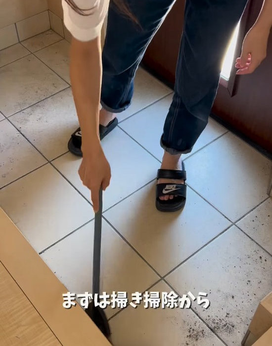 ほうきで玄関を掃き掃除する様子