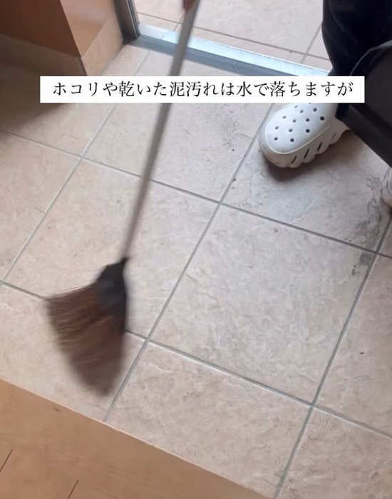 玄関をほうきで掃除している様子