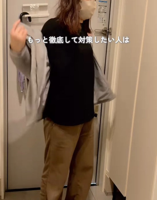 玄関で上着を脱ぐ女性